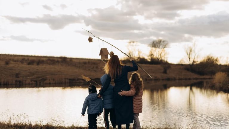 Family enjoying quality time by the lake at sunset with birdhouses.