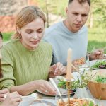 A family shares a meal outdoors, enjoying fresh and vibrant salads.