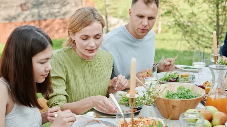 A family shares a meal outdoors, enjoying fresh and vibrant salads.